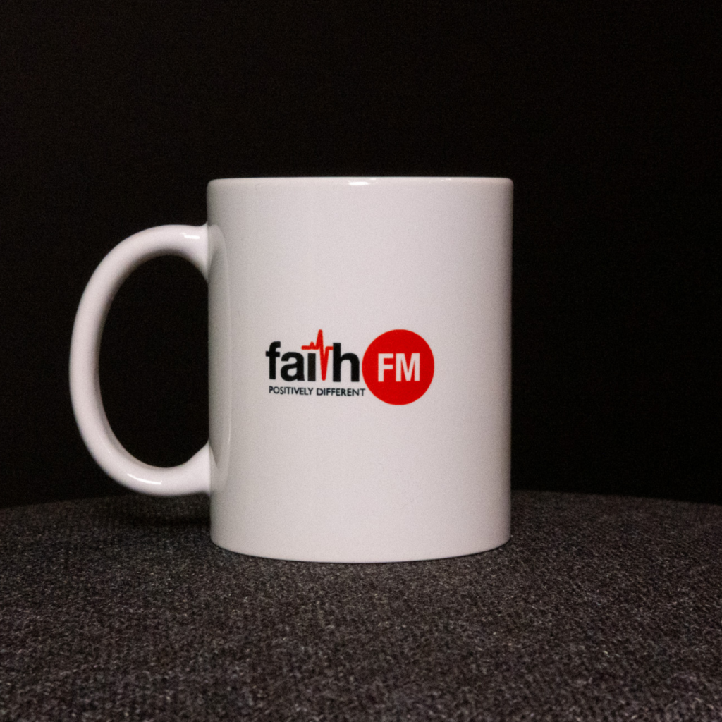A white mug with the Faith FM logo.